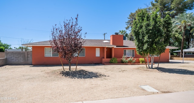 ranch-style home with stucco siding, a chimney, and fence