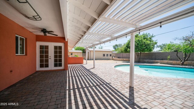 view of swimming pool with a fenced in pool, a fenced backyard, an outdoor structure, french doors, and a patio