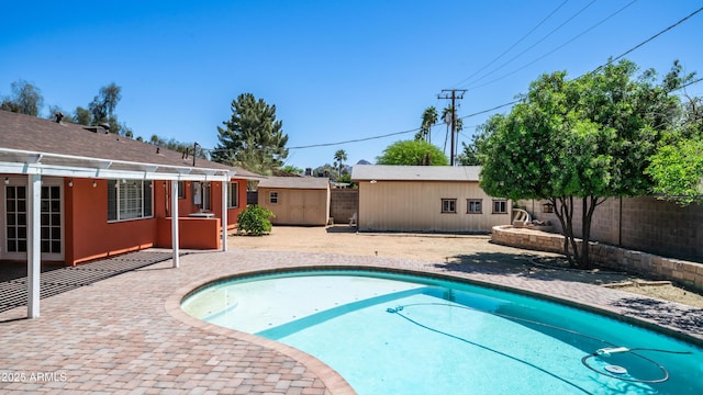 view of swimming pool featuring a fenced backyard, a patio area, a fenced in pool, and an outbuilding