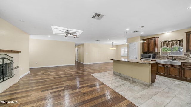 kitchen with stainless steel microwave, open floor plan, a sink, and visible vents