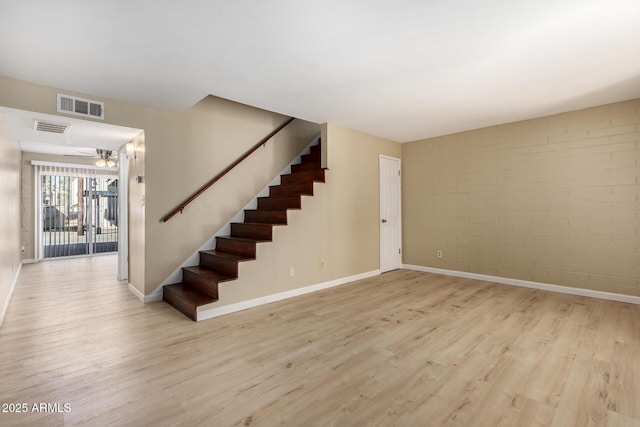 stairs featuring brick wall, baseboards, visible vents, and wood finished floors