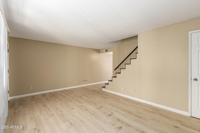 empty room featuring light wood-style flooring, stairs, baseboards, and visible vents