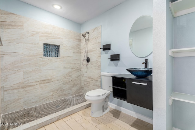 bathroom featuring vanity, a tile shower, and toilet