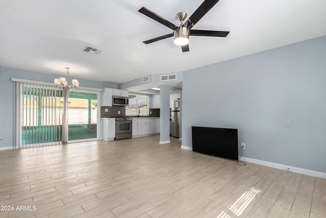 unfurnished living room with light wood-type flooring and ceiling fan with notable chandelier