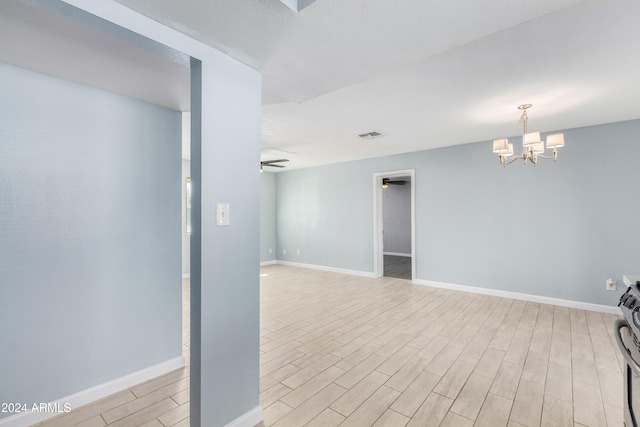 unfurnished room featuring an inviting chandelier and light wood-type flooring