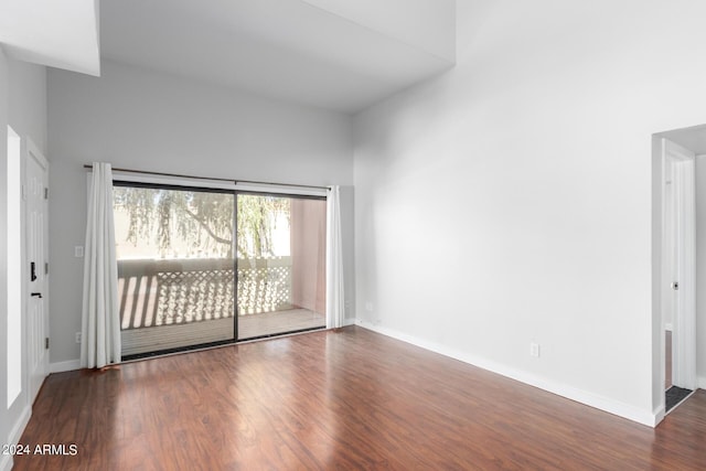 empty room featuring a towering ceiling and dark hardwood / wood-style flooring