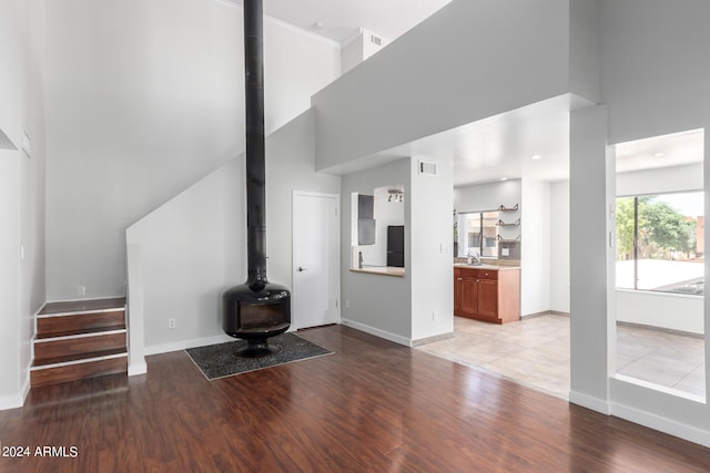 unfurnished living room with sink, a towering ceiling, and light wood-type flooring