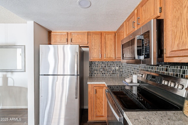 kitchen with brown cabinets, appliances with stainless steel finishes, and decorative backsplash