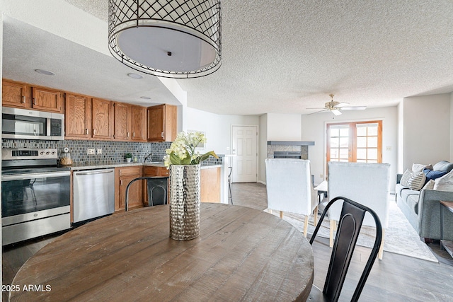 dining room featuring a textured ceiling, ceiling fan, a fireplace, and wood finished floors