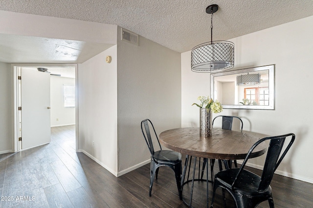 dining space featuring dark wood-style flooring, visible vents, a textured ceiling, and baseboards