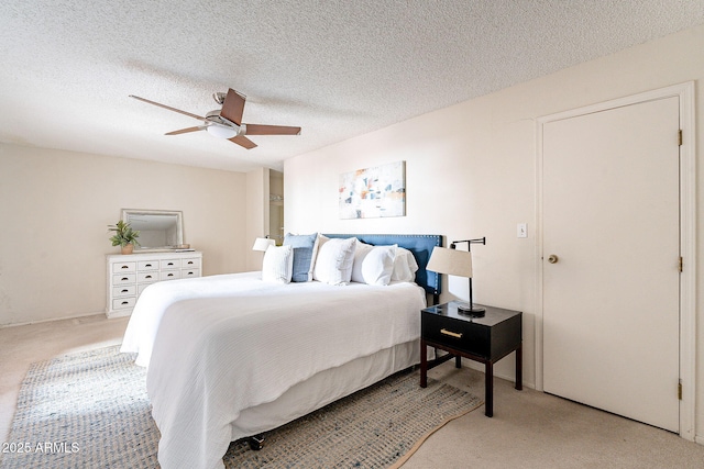 bedroom featuring light carpet, ceiling fan, and a textured ceiling