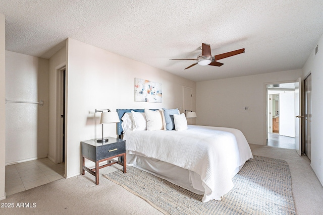 bedroom with a textured ceiling, a ceiling fan, and light colored carpet