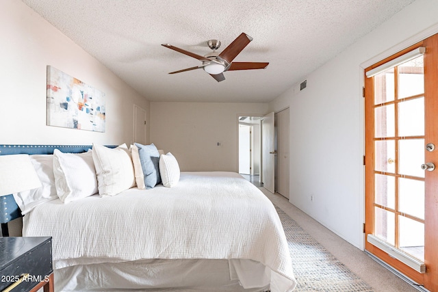 bedroom with a ceiling fan, visible vents, a textured ceiling, and light colored carpet