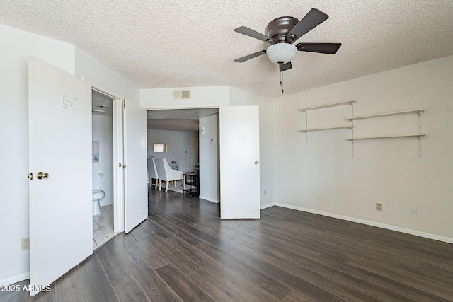 unfurnished room with dark wood-style flooring, visible vents, a textured ceiling, and baseboards