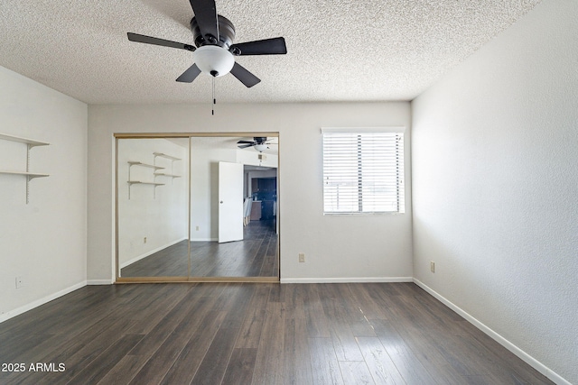 empty room with dark wood-style floors, a textured ceiling, and baseboards