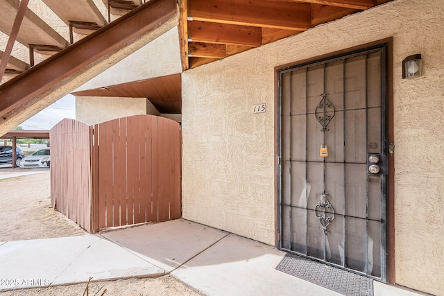 doorway to property with a gate and stucco siding