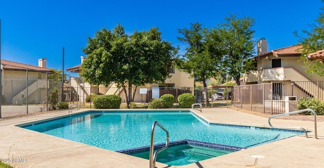 community pool featuring a patio area, a hot tub, and fence