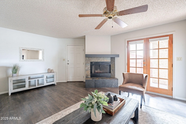 living area featuring baseboards, wood finished floors, a textured ceiling, french doors, and a fireplace