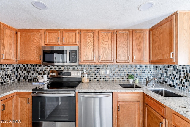 kitchen featuring brown cabinetry, decorative backsplash, appliances with stainless steel finishes, a textured ceiling, and a sink