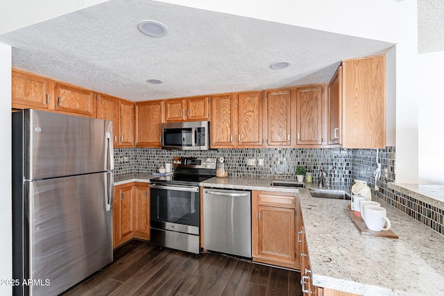 kitchen featuring stainless steel appliances, dark wood-type flooring, a sink, and decorative backsplash