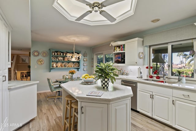 kitchen with dishwasher, sink, white cabinetry, and a center island