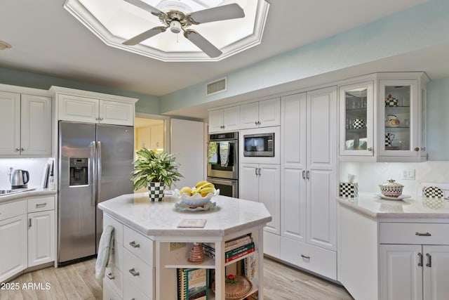 kitchen with ceiling fan, white cabinets, appliances with stainless steel finishes, and light wood-type flooring