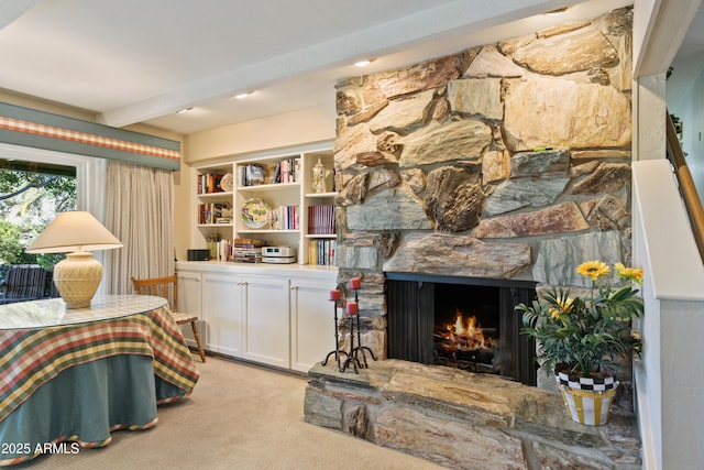 sitting room with beam ceiling, built in features, light carpet, and a fireplace