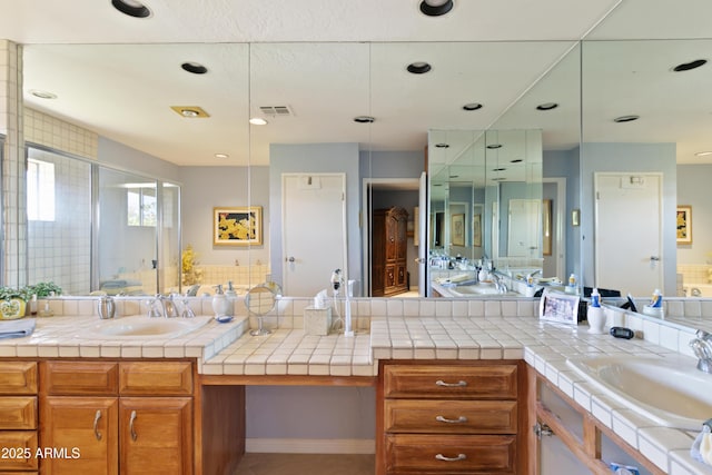 bathroom with a shower with door and vanity