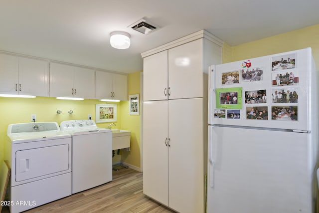 laundry room featuring cabinets, washer and clothes dryer, and light wood-type flooring