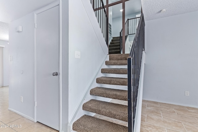 staircase featuring a textured ceiling and tile patterned flooring