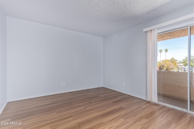 unfurnished room featuring light hardwood / wood-style flooring and a textured ceiling