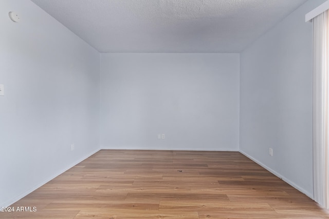 empty room featuring a textured ceiling and light wood-type flooring