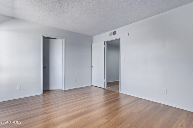 unfurnished room featuring a textured ceiling and light wood-type flooring