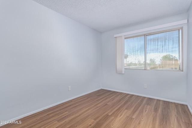 empty room featuring a textured ceiling and light hardwood / wood-style flooring