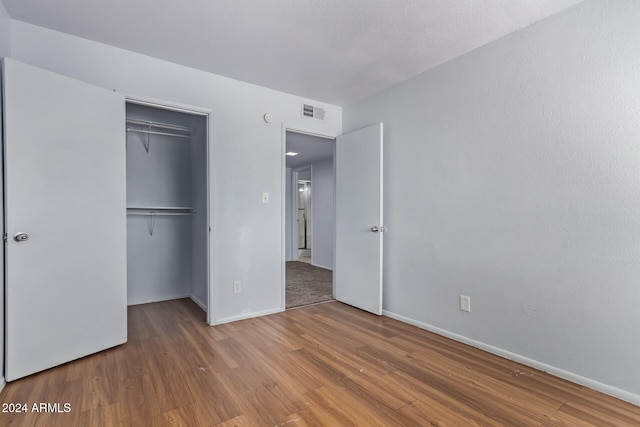 unfurnished bedroom with hardwood / wood-style flooring and a closet