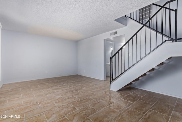 stairway featuring a textured ceiling