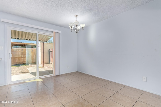 unfurnished room featuring a notable chandelier, a healthy amount of sunlight, a textured ceiling, and light tile patterned flooring