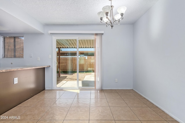 unfurnished dining area featuring an inviting chandelier, a textured ceiling, and light tile patterned floors