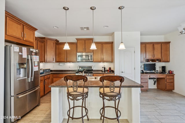 kitchen with an island with sink, a breakfast bar area, decorative light fixtures, and appliances with stainless steel finishes