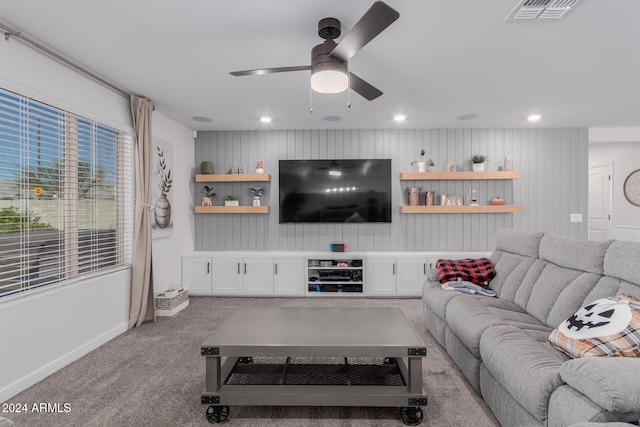 living room featuring wooden walls, light carpet, and ceiling fan