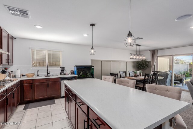 kitchen featuring sink, appliances with stainless steel finishes, hanging light fixtures, a kitchen island, and decorative backsplash