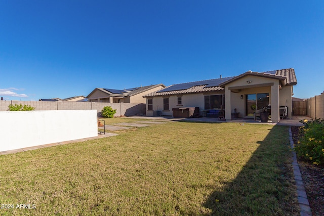 back of house featuring a lawn, solar panels, a patio, and a jacuzzi