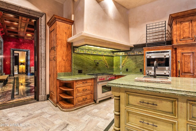 kitchen featuring stainless steel appliances, beam ceiling, coffered ceiling, light stone countertops, and custom exhaust hood