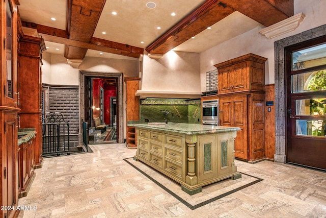 kitchen featuring sink, oven, beamed ceiling, a kitchen island, and light stone countertops