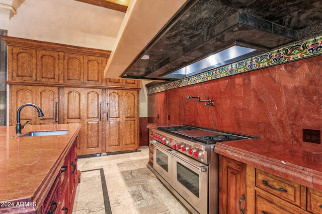 kitchen with double oven range, custom range hood, and sink