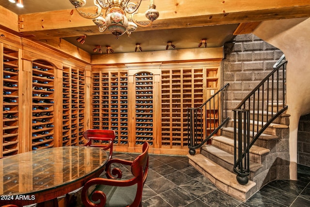 wine room featuring a notable chandelier and beam ceiling