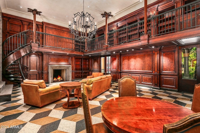 dining room with crown molding, a notable chandelier, wooden walls, and a high ceiling