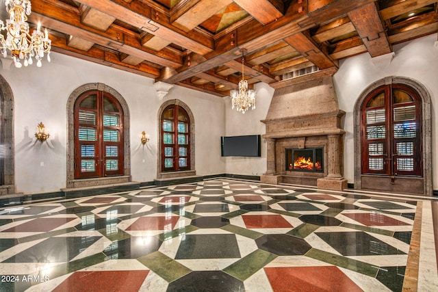 living room featuring beam ceiling, coffered ceiling, a premium fireplace, decorative columns, and french doors