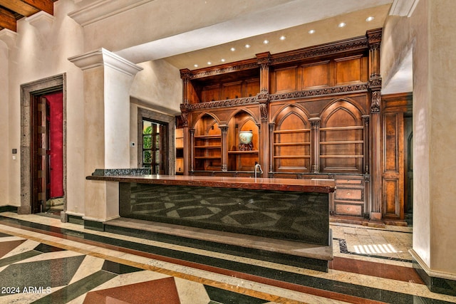 bar featuring sink, ornate columns, and a towering ceiling