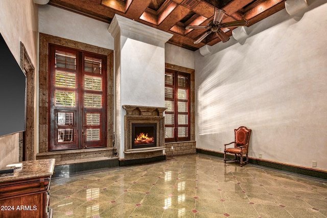 8100 N 68th St, Paradise Valley, AZ 85253 - unfurnished living room featuring coffered ceiling, beamed ceiling, a ceiling fan, a towering ceiling, and a lit fireplace